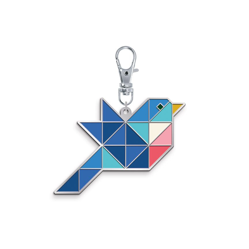 Enamel charm shaped like a patchwork bird in shades of blue with pink and yellow accents, on a silver clasp.