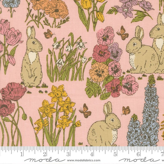 A close-up of a fabric pattern featuring rabbits, daffodils, poppies, and butterflies on a light pink background, with a ruler along the bottom edge showing the scale of the print.