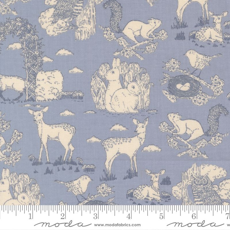A fabric pattern featuring a sky blue background with a cream-colored toile print of woodland animals, including deer, rabbits, squirrels, birds, and trees. A white ruler is shown along the bottom edge to indicate scale.