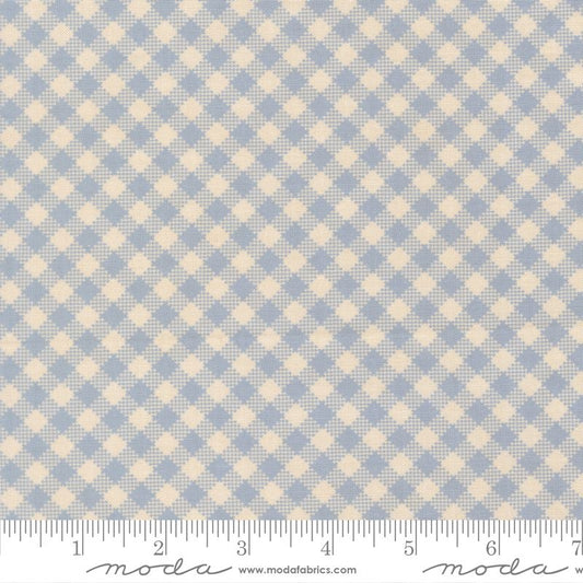 A close-up of a fabric pattern showing a light blue and cream gingham check design, with a measuring ruler along the bottom edge for scale. The brand name 'Moda Fabrics' is visible at the bottom.