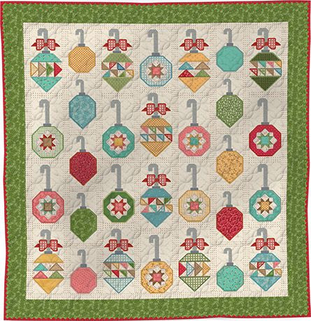 A quilted patchwork quilt featuring rows of colorful Christmas ornaments hanging from gray hooks, set on an off-white background with a green patterned border.
