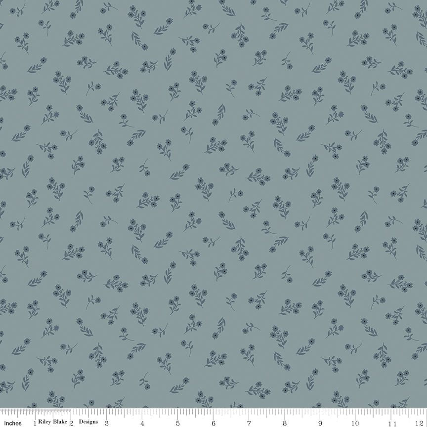 A repeating floral pattern on a muted blue-gray background, with small dark blue flowers and leaves. A ruler strip is visible along the bottom edge showing scale.