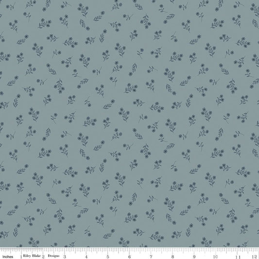 A repeating floral pattern on a muted blue-gray background, with small dark blue flowers and leaves. A ruler strip is visible along the bottom edge showing scale.