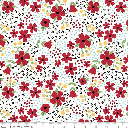 A repeating floral pattern on a white background with red flowers, small yellow flower, black flower motifs, ladybugs and light blue polka dots. A ruler along the bottom edge shows the pattern scale.