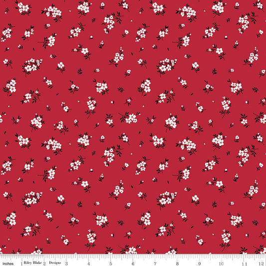 Red fabric with a repeating white and black cherry blossom floral pattern, shown flat with a ruler at the bottom indicating scale.