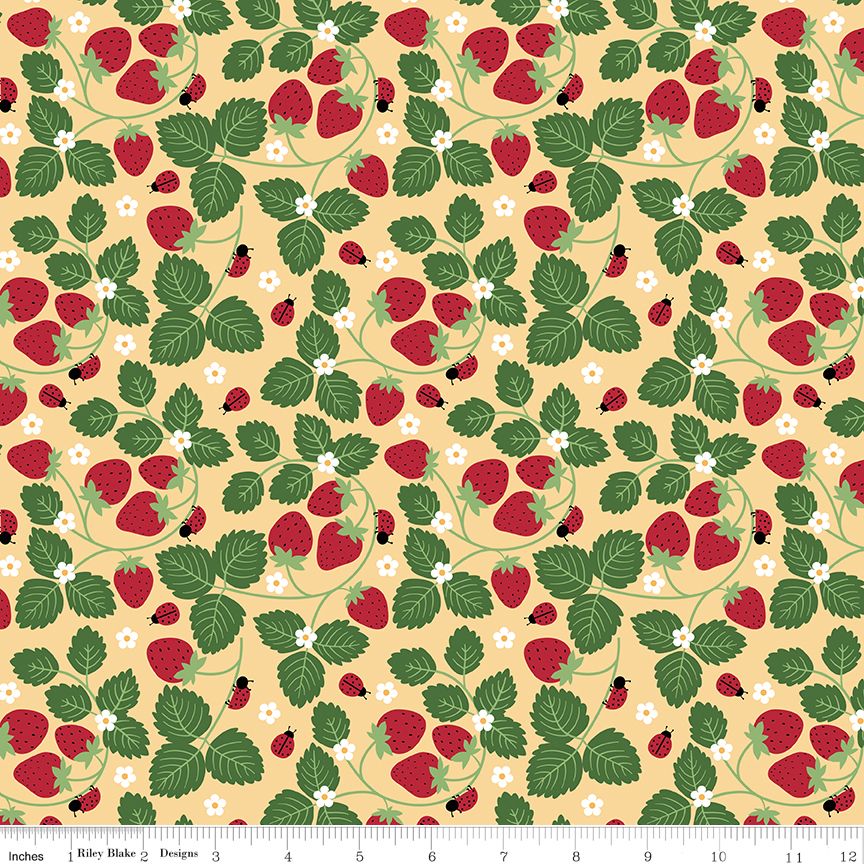 A repeating fabric pattern featuring red strawberries, green leaves, small white flowers, and ladybugs on a pale yellow background, with a ruler along the bottom edge showing scale.