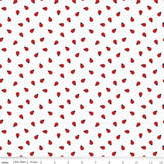 A repeating pattern of red ladybugs with black heads and legs on a white background with tiny blue-gray dots. A ruler along the bottom edge shows the scale of the print.