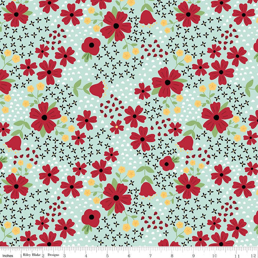 A repeating floral fabric pattern with red flowers, green leaves, black flowers, and small yellow flowers and ladybugs on a pale blue background. A ruler strip appears along the bottom edge.