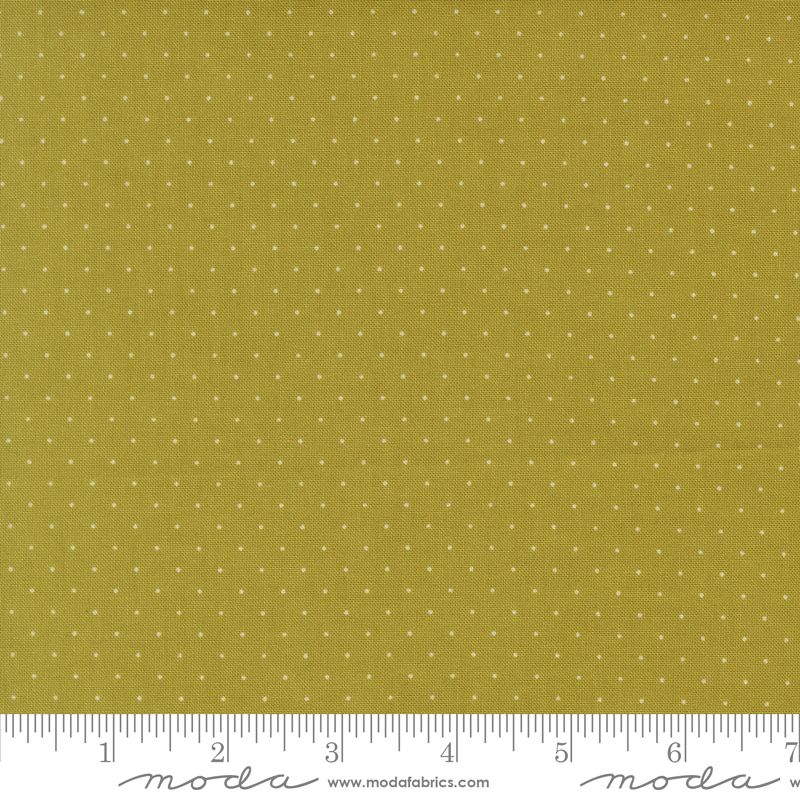 A close-up of a fabric swatch showing a rich sage background with a small white polka dot pattern, with a ruler at the bottom indicating scale and Moda Fabrics branding.