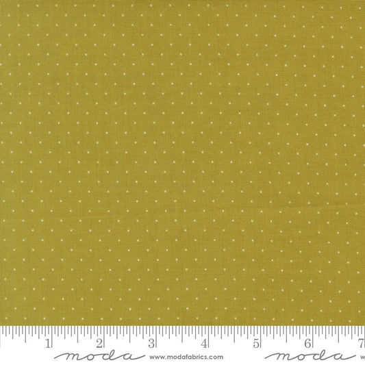 A close-up of a fabric swatch showing a rich sage background with a small white polka dot pattern, with a ruler at the bottom indicating scale and Moda Fabrics branding.