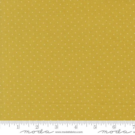 Yellow fabric with a small white polka dot pattern, shown with a measuring ruler at the bottom to indicate scale. The brand name 'Moda Fabrics' is visible on the ruler.
