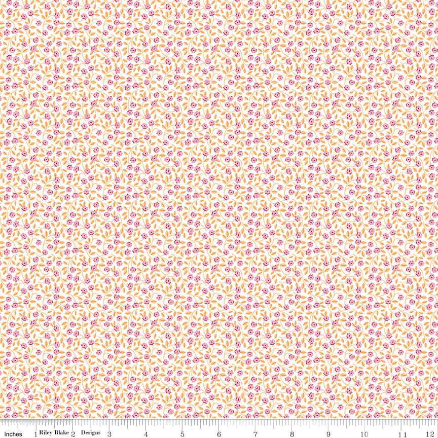 A close-up of a repeating fabric pattern featuring small pink flowers and yellow-orange leaves on a white background, with a ruler along the bottom edge showing scale.