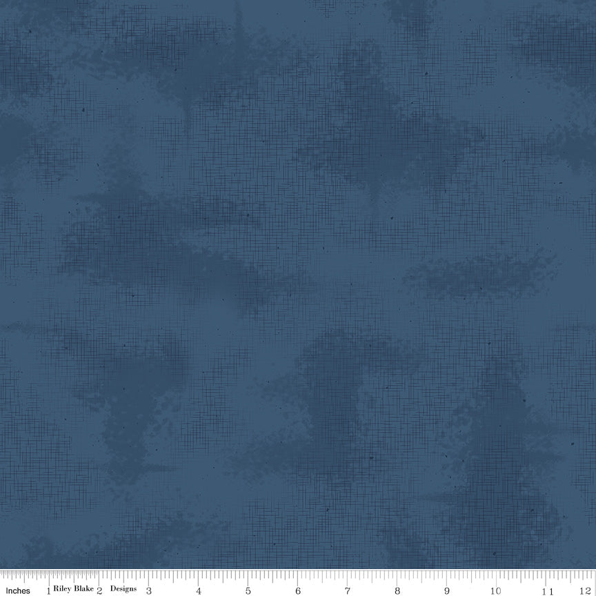 A close-up of a blue fabric with a subtle textured pattern, featuring a white ruler along the bottom edge.